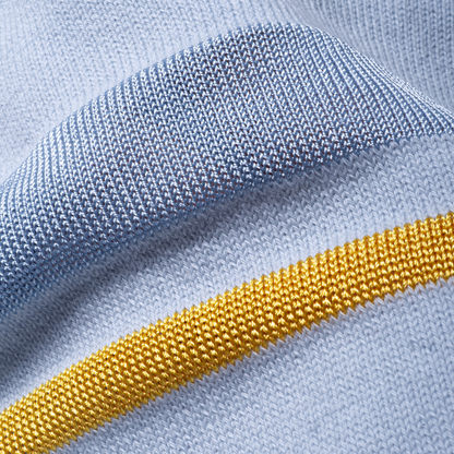 Sold at Bombon and designed by Gensami, a blue knit baby blanket with tonal stripe detailing and a yellow border