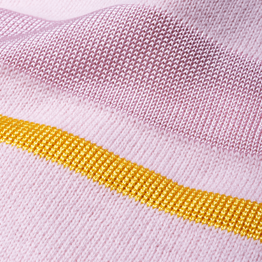 Sold at Bombon and designed by Gensami, a pink newborn layette set featuring a knit jumpsuit, hat, socks, and matching blanket with yellow stripe accents