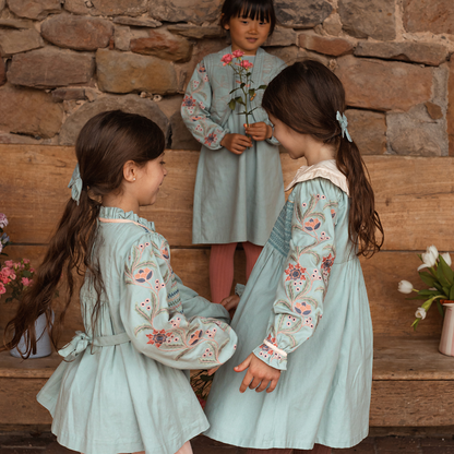 sold at Bombon shop, designed by Bachaa, Blouse/Short dress, Blue color, Organic cotton twill (167 g/m²), Plain lining in organic cotton voile, Long embroidered and elasticated sleeves, Smocked chest, Ruffled collar, Tone-on-tone buttons and belt at the back. Model view