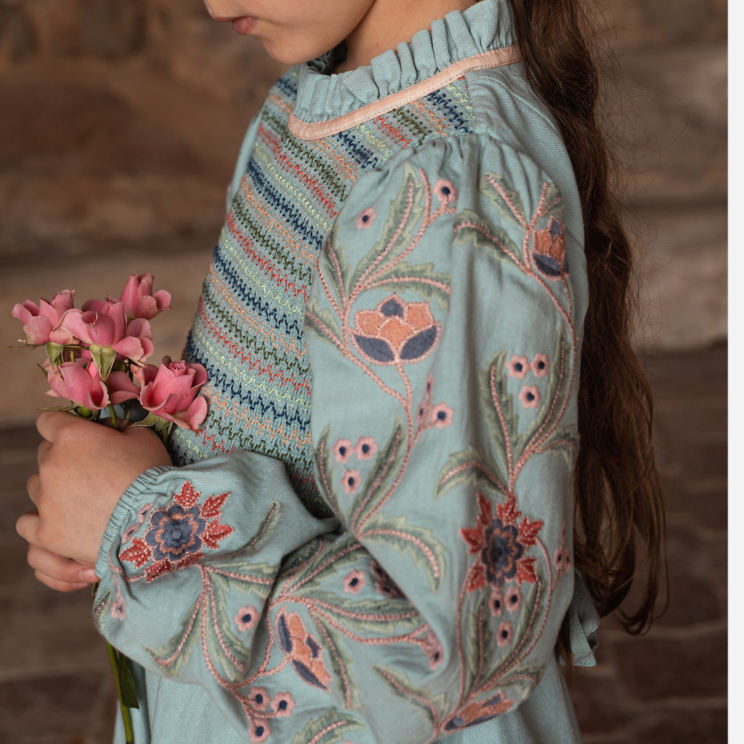 sold at Bombon shop, designed by Bachaa, Blouse/Short dress, Blue color, Organic cotton twill (167 g/m²), Plain lining in organic cotton voile, Long embroidered and elasticated sleeves, Smocked chest, Ruffled collar, Tone-on-tone buttons and belt at the back. sleeve detail model view