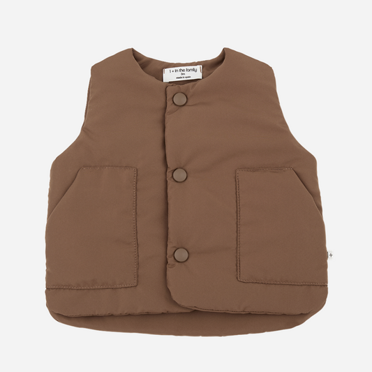 Sold at Bombon shop, designed by 1+ in the family — brown padded baby vest with front patch pockets and snap-button closure, laid flat on a white background.