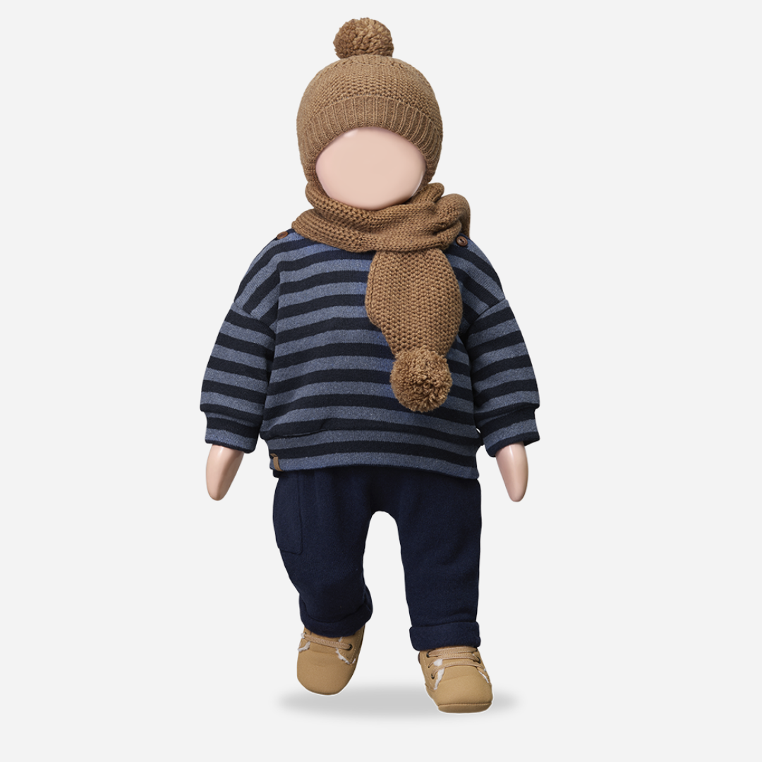 Doll wearing a striped sweater, navy pants, brown shoes, and a matching hat and scarf on a light gray background