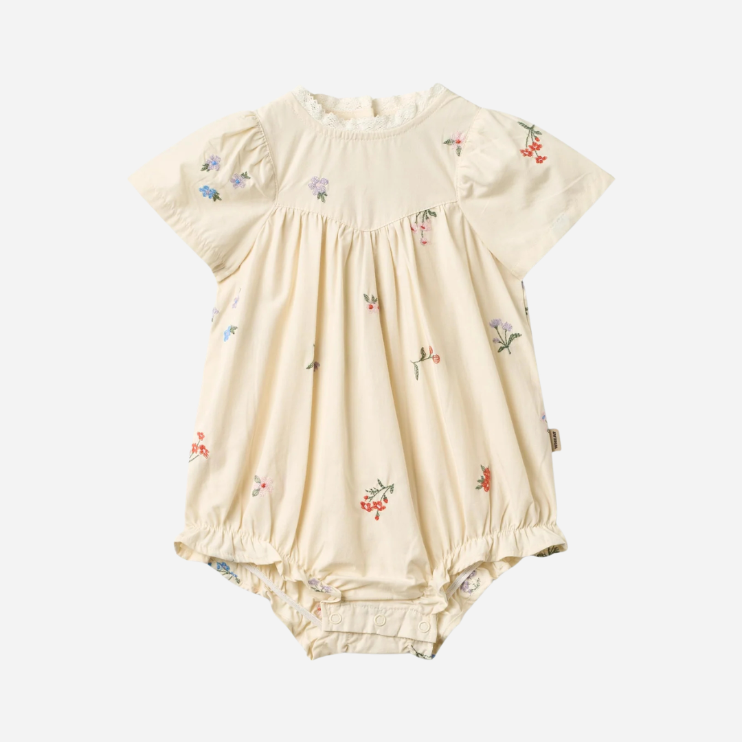 Sold at Bombon Shop, designed by Wheat, ivory organic cotton baby romper with delicate embroidered flowers and soft gathered detailing.