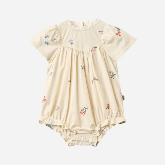Sold at Bombon Shop, designed by Wheat, ivory organic cotton baby romper with delicate embroidered flowers and soft gathered detailing.