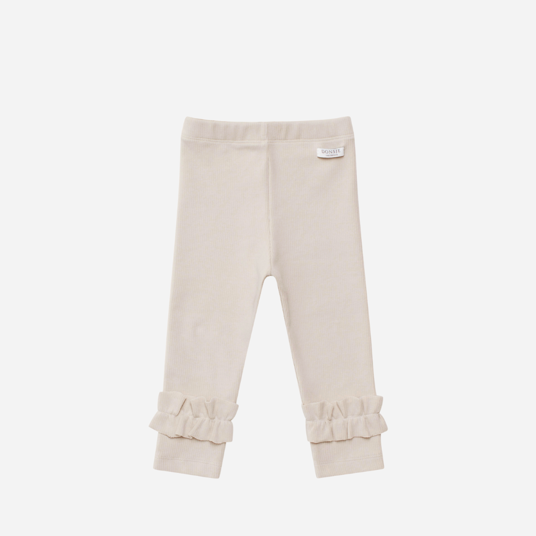 Sold at Bombon shop, designed by Donsje from Amsterdam, these leggings in a soft sand color and ruffle detail in the bottom leg for baby gris and toddler are the perfect piece for pre fall all the way through winter.  front view