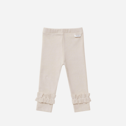 Sold at Bombon shop, designed by Donsje from Amsterdam, these leggings in a soft sand color and ruffle detail in the bottom leg for baby gris and toddler are the perfect piece for pre fall all the way through winter.  front view