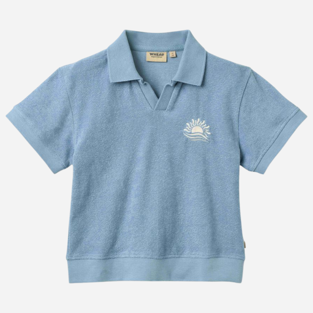 Sold at Bombon Shop, designed by Wheat, faded denim organic cotton short sleeve polo shirt with classic collar and soft blue washed tone.