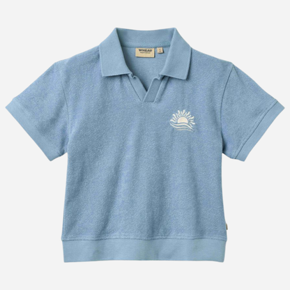 Sold at Bombon Shop, designed by Wheat, faded denim organic cotton short sleeve polo shirt with classic collar and soft blue washed tone.