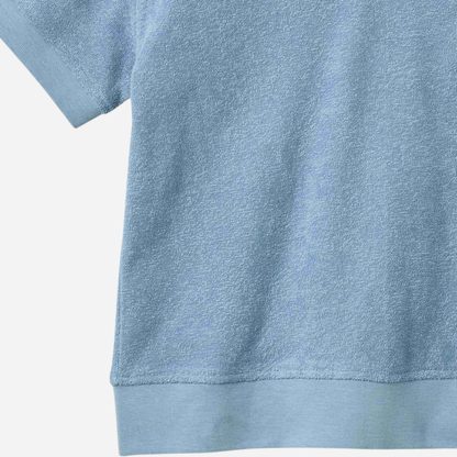 Sold at Bombon Shop, designed by Wheat, faded denim organic cotton short sleeve polo shirt with classic collar and soft blue washed tone.