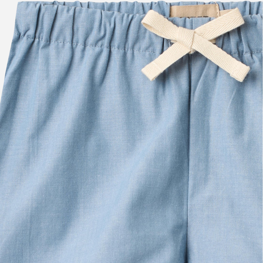 Sold at Bombon Shop, designed by Wheat, blue chambray organic cotton kids shorts with elastic waistband and drawstring detail.