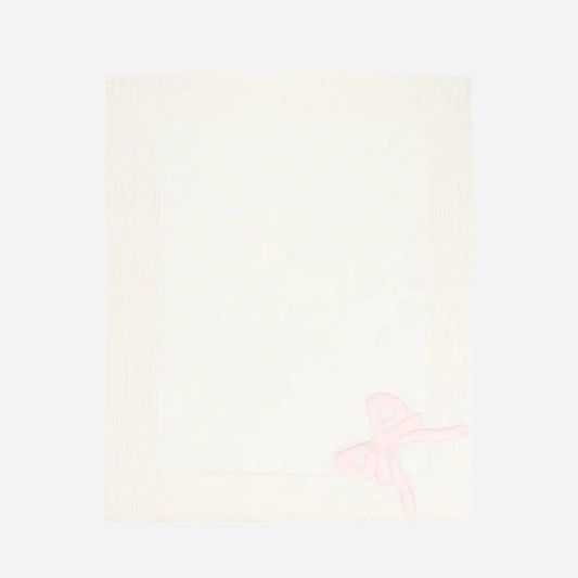 Sold at Bombon and designed by Gensami, a white merino wool baby blanket featuring a pink satin bow in one corner and yellow trim along the edge.