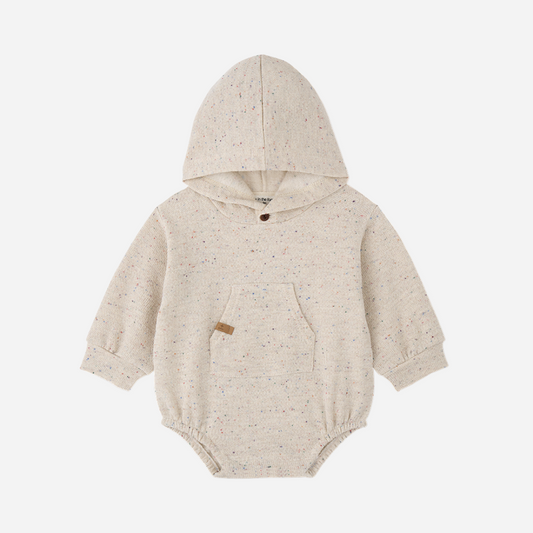 Sold at Bombon shop, designed by 1+ in the family — speckled cream baby romper with hood, long sleeves, and front kangaroo pocket.