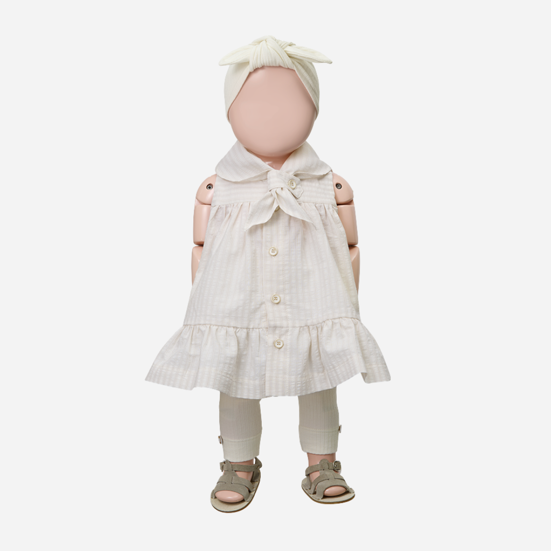 Sold at Bombon Shop, designed by 1+ in the family, beige baby dress with textured vertical stripe cotton fabric and sailor-style collar.