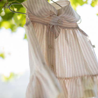 Sold at Bombon Shop, designed by 1+ in the family, beige baby dress with textured vertical stripe cotton fabric and sailor-style collar.