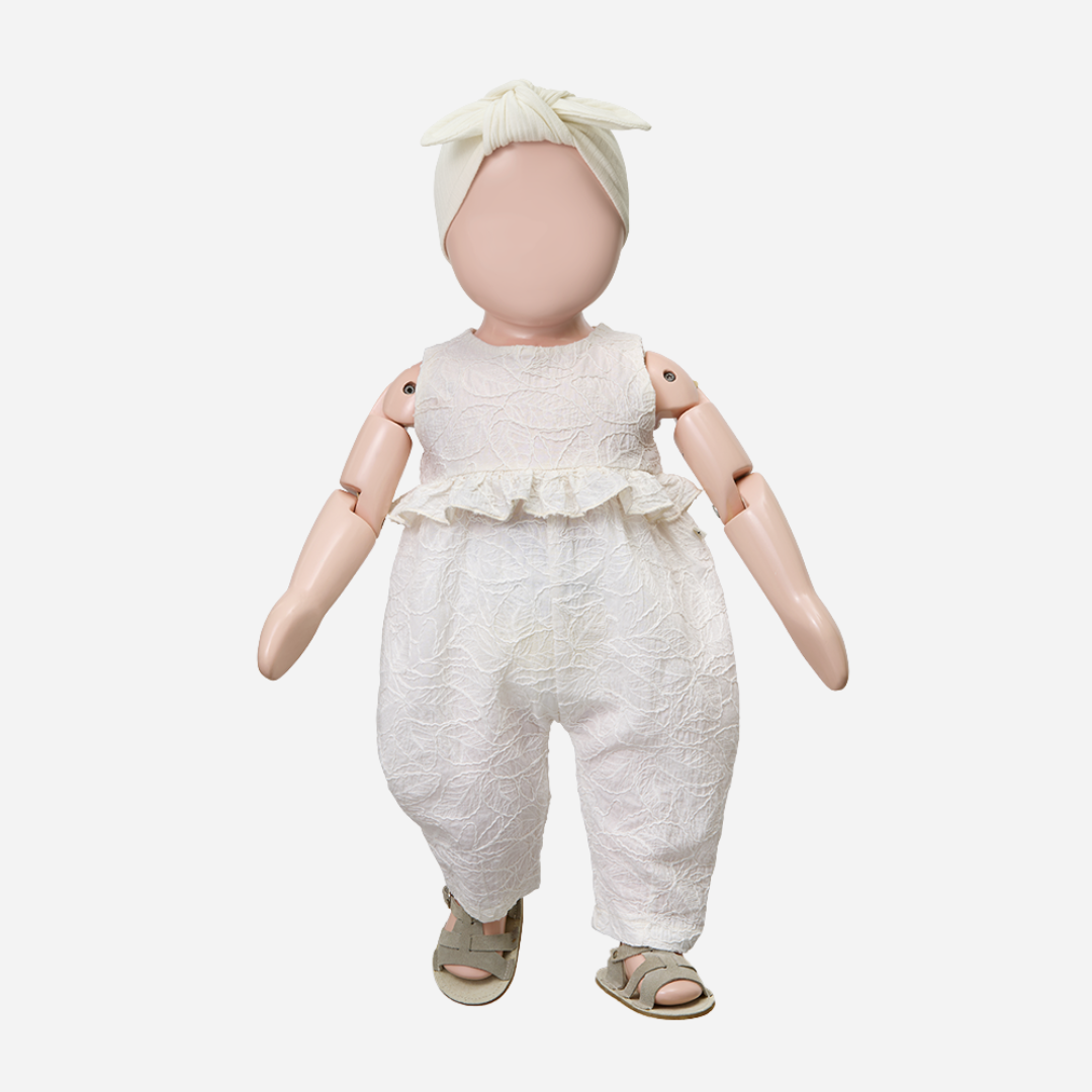 Sold at Bombon Shop, designed by 1+ in the family, off-white baby overall with textured cotton fabric and delicate ruffle detail across the chest.