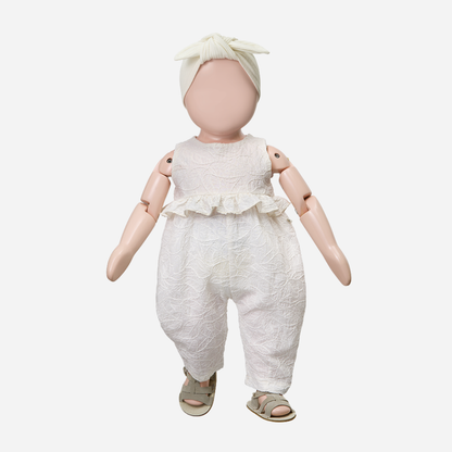 Sold at Bombon Shop, designed by 1+ in the family, off-white baby overall with textured cotton fabric and delicate ruffle detail across the chest.