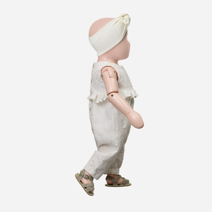 Sold at Bombon Shop, designed by 1+ in the family, off-white baby overall with textured cotton fabric and delicate ruffle detail across the chest.