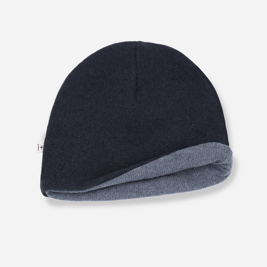Sold at Bombon shop, designed by 1+ in the family — reversible knit baby beanie in navy and denim blue with soft, folded edge.