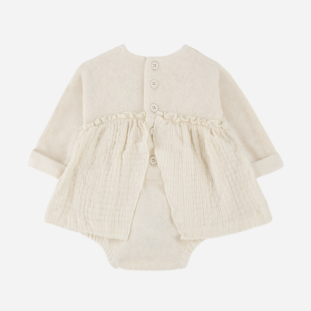 Sold at Bombon shop, designed by 1+ in the family — cream long-sleeve baby dress romper with ruffled gauze skirt and knit bodice. back