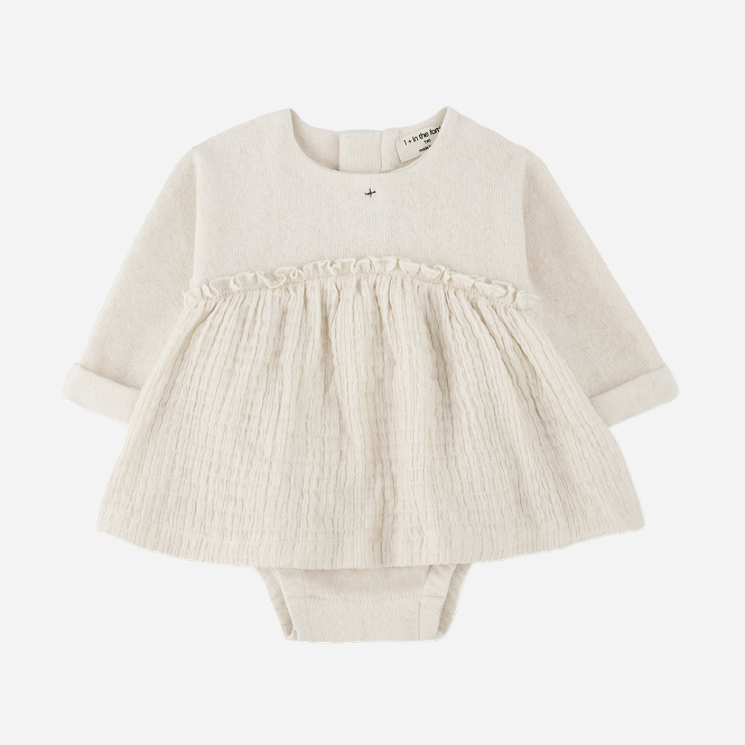 Sold at Bombon shop, designed by 1+ in the family — cream long-sleeve baby dress romper with ruffled gauze skirt and knit bodice. front