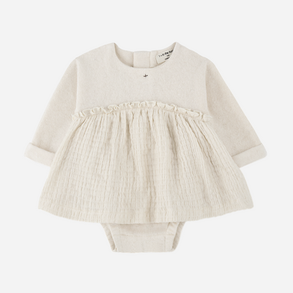 Sold at Bombon shop, designed by 1+ in the family — cream long-sleeve baby dress romper with ruffled gauze skirt and knit bodice. front