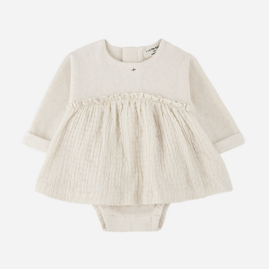 Sold at Bombon shop, designed by 1+ in the family — cream long-sleeve baby dress romper with ruffled gauze skirt and knit bodice. front