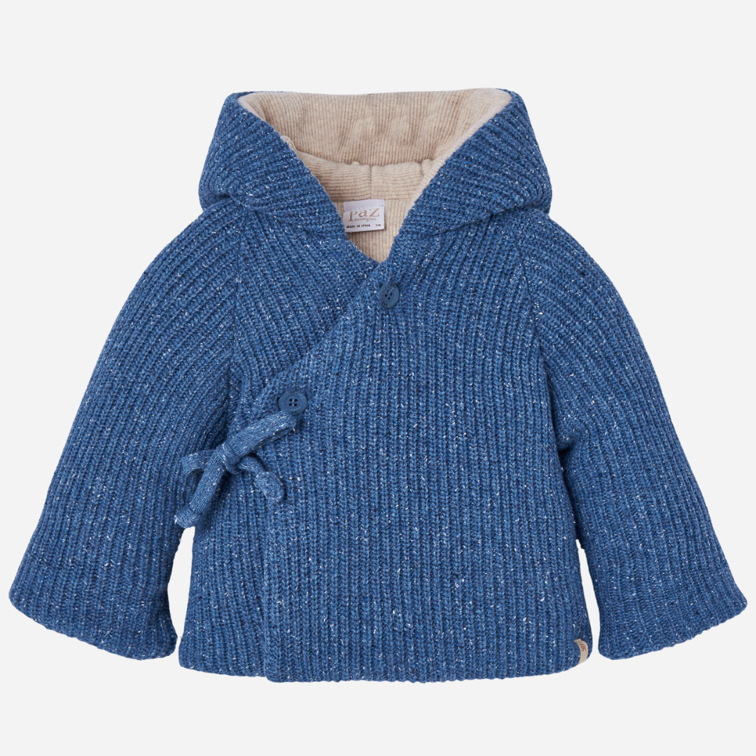 Sold at Bombon shop, designed by Paz Rodriguez. Baby and toddler knit coat in blue with wrap closure, side ties, buttons, and beige lining. front