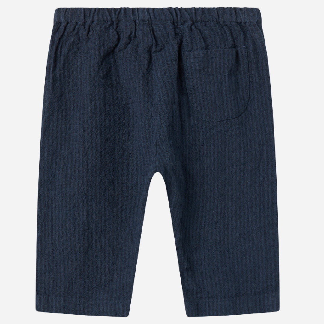 Sold at Bombon shop, designed by MarMar Copenhagen — navy 100% cotton textured baby pants with elastic waistband, part of a matching set.