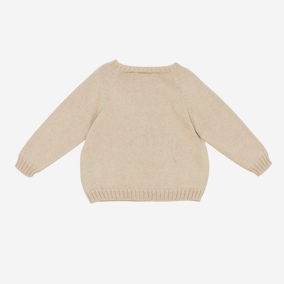 Sold at Bombon shop, designed by Fina Ejerique, a beige knit baby sweater with a penguin motif wearing a blue scarf. back