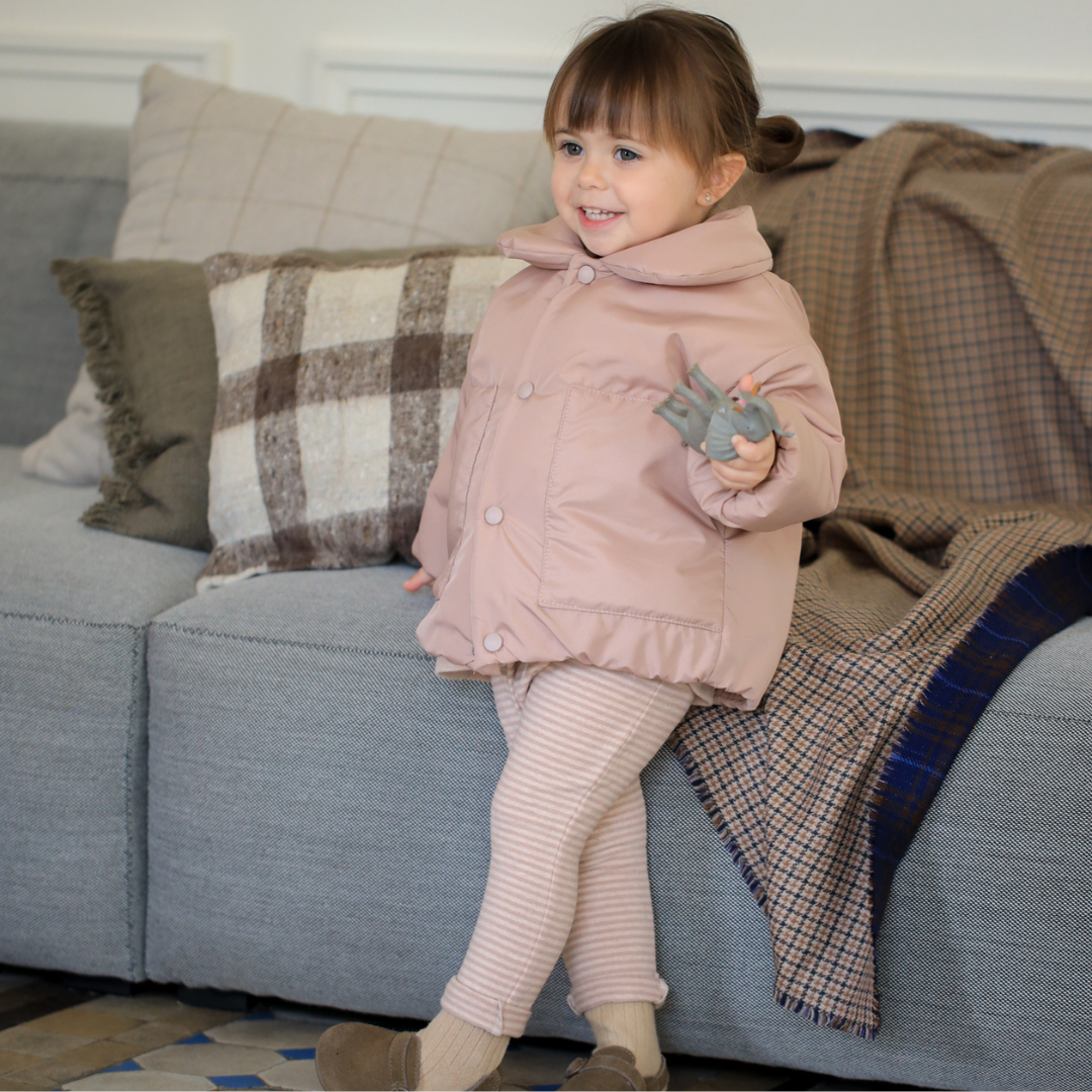 Sold at Bombon shop, designed by 1+ in the family — nude striped baby leggings with elastic waist and single button detail. model