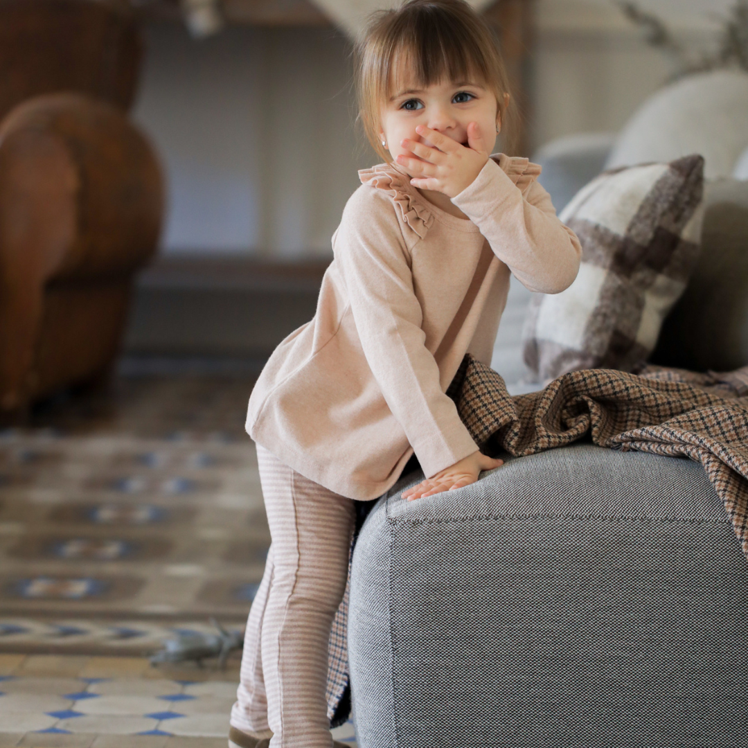 Sold at Bombon shop, designed by 1+ in the family — nude striped baby leggings with elastic waist and single button detail. model