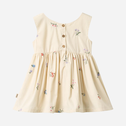 Sold at Bombon Shop, designed by Wheat, ivory organic cotton pinafore dress with embroidered floral details and gathered skirt.