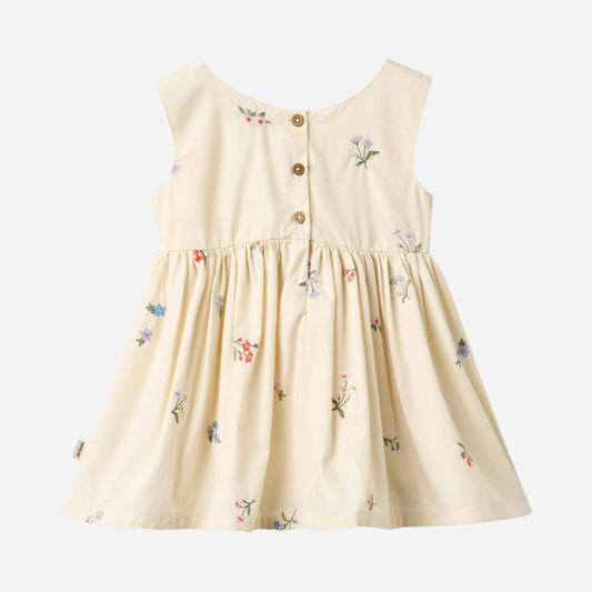 Sold at Bombon Shop, designed by Wheat, ivory organic cotton pinafore dress with embroidered floral details and gathered skirt.