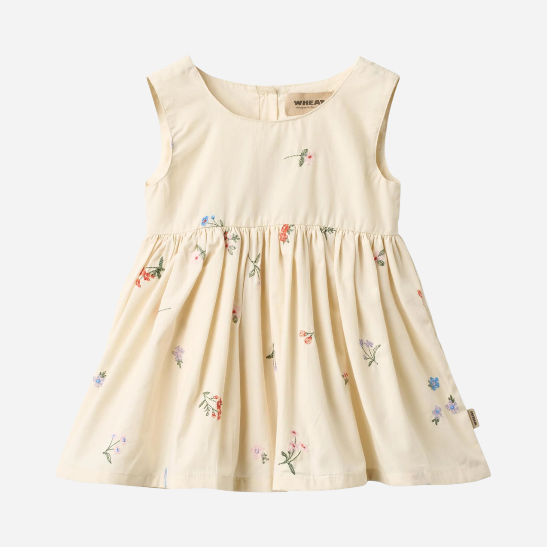 Sold at Bombon Shop, designed by Wheat, ivory organic cotton pinafore dress with embroidered floral details and gathered skirt.