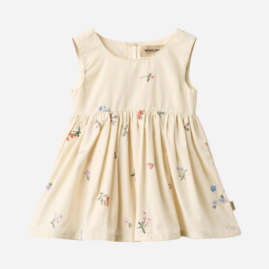 Sold at Bombon Shop, designed by Wheat, ivory organic cotton pinafore dress with embroidered floral details and gathered skirt.