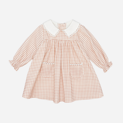 Sold at Bombon shop, designed by Fina Ejerique, a blush-pink gingham baby dress with white collar, lace trim, front pockets, and long sleeves. front