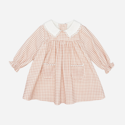 Sold at Bombon shop, designed by Fina Ejerique, a blush-pink gingham baby dress with white collar, lace trim, front pockets, and long sleeves. front