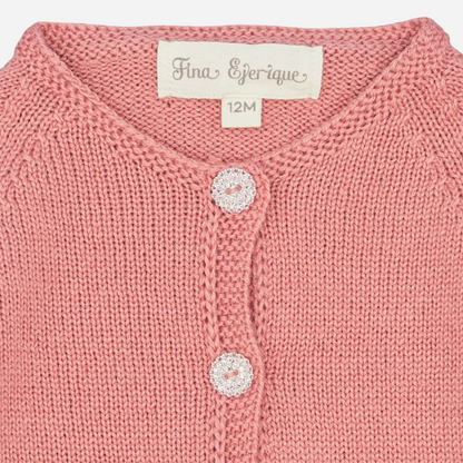 Sold at Bombon shop, designed by Fina Ejerique, a rose-pink knit baby cardigan with scalloped trim and front buttons. zoom