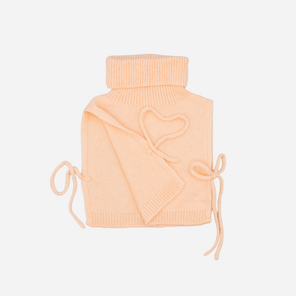 Sold at Bombon shop, designed by Fina Ejerique, pink knit vest with turtleneck and side ties, pairs perfectly with the floral blouse and beige textured skirt. side