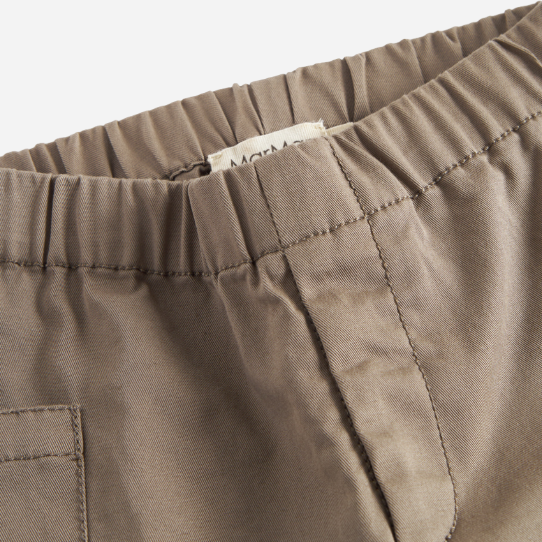 Sold at Bombon shop, designed by MarMar Copenhagen — taupe 100% cotton baby pants with front pockets and elastic waistband, pairs perfectly with the striped knit cardigan