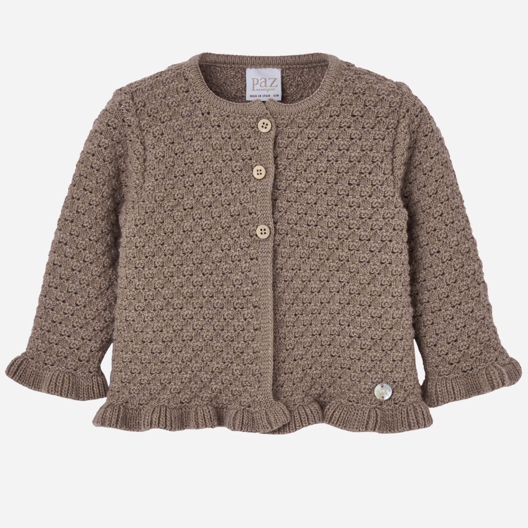 Sold at Bombon shop, designed by Paz Rodriguez. Brown knit baby cardigan with textured finish, wooden buttons, and ruffled trim.