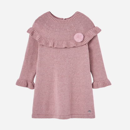 Sold at Bombon shop, designed by Paz Rodriguez. Pink knitted baby girl dress with ruffle trim, long sleeves, and pom-pom detail on the chest.