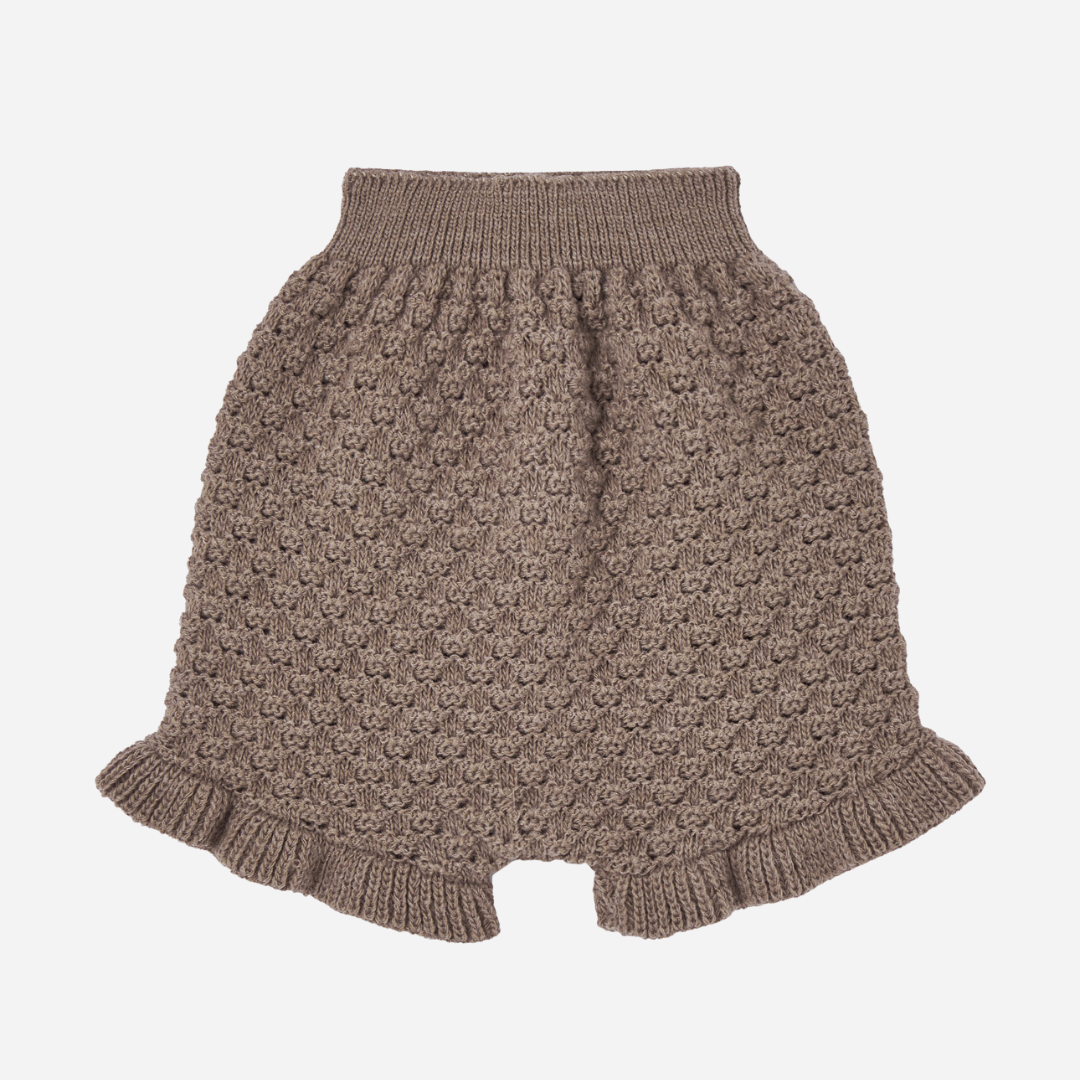 Sold at Bombon shop, designed by Paz Rodriguez. Brown knit baby shorts with ruffled hem and textured pattern.