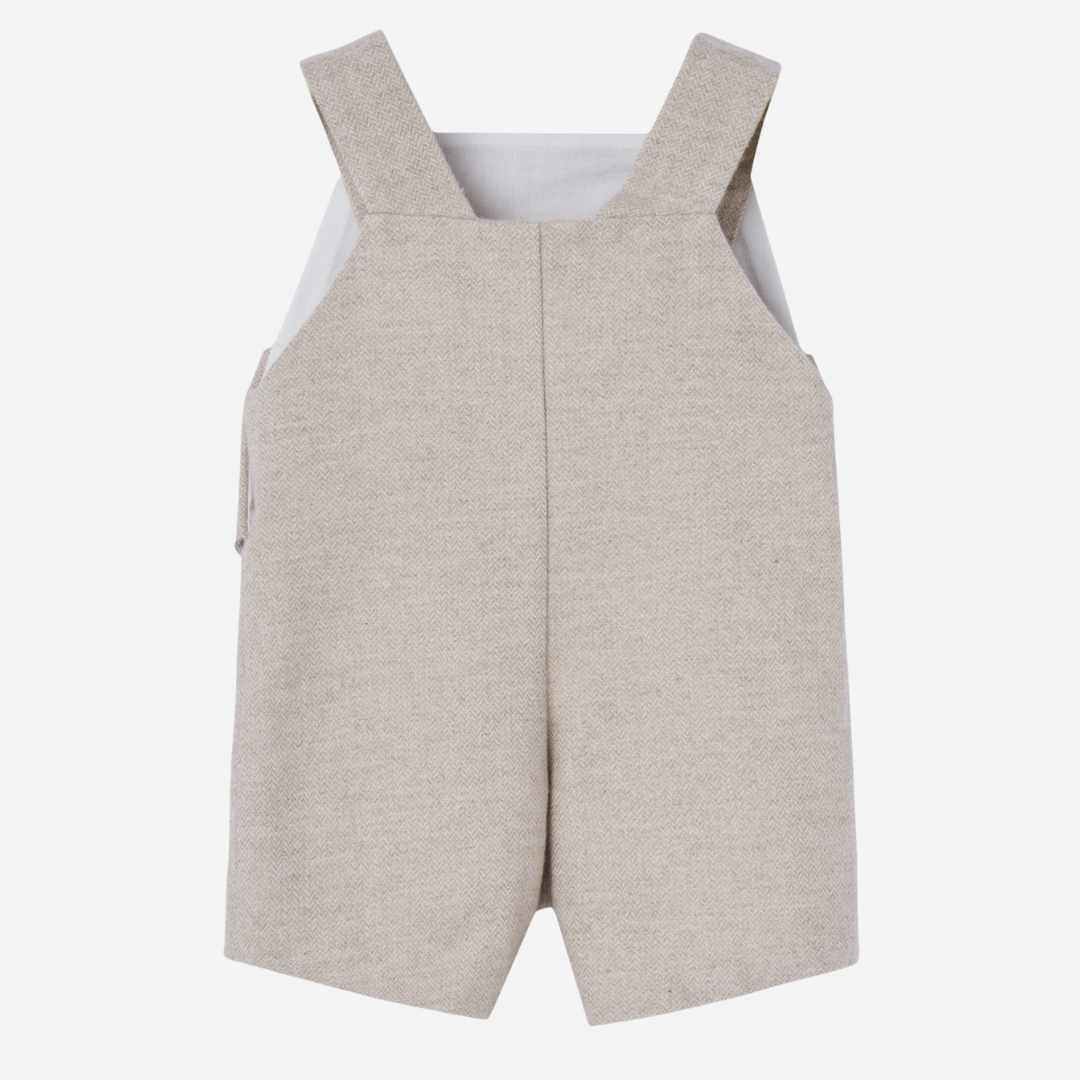 Sold at Bombon shop, designed by Paz Rodriguez. Beige herringbone baby overall with buttoned straps and side flap details.