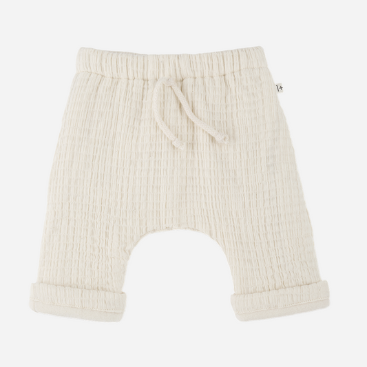 Sold at Bombon shop, designed by 1+ in the family — cream textured cotton muslin baby pants with rolled cuffs and adjustable drawstring waist. front