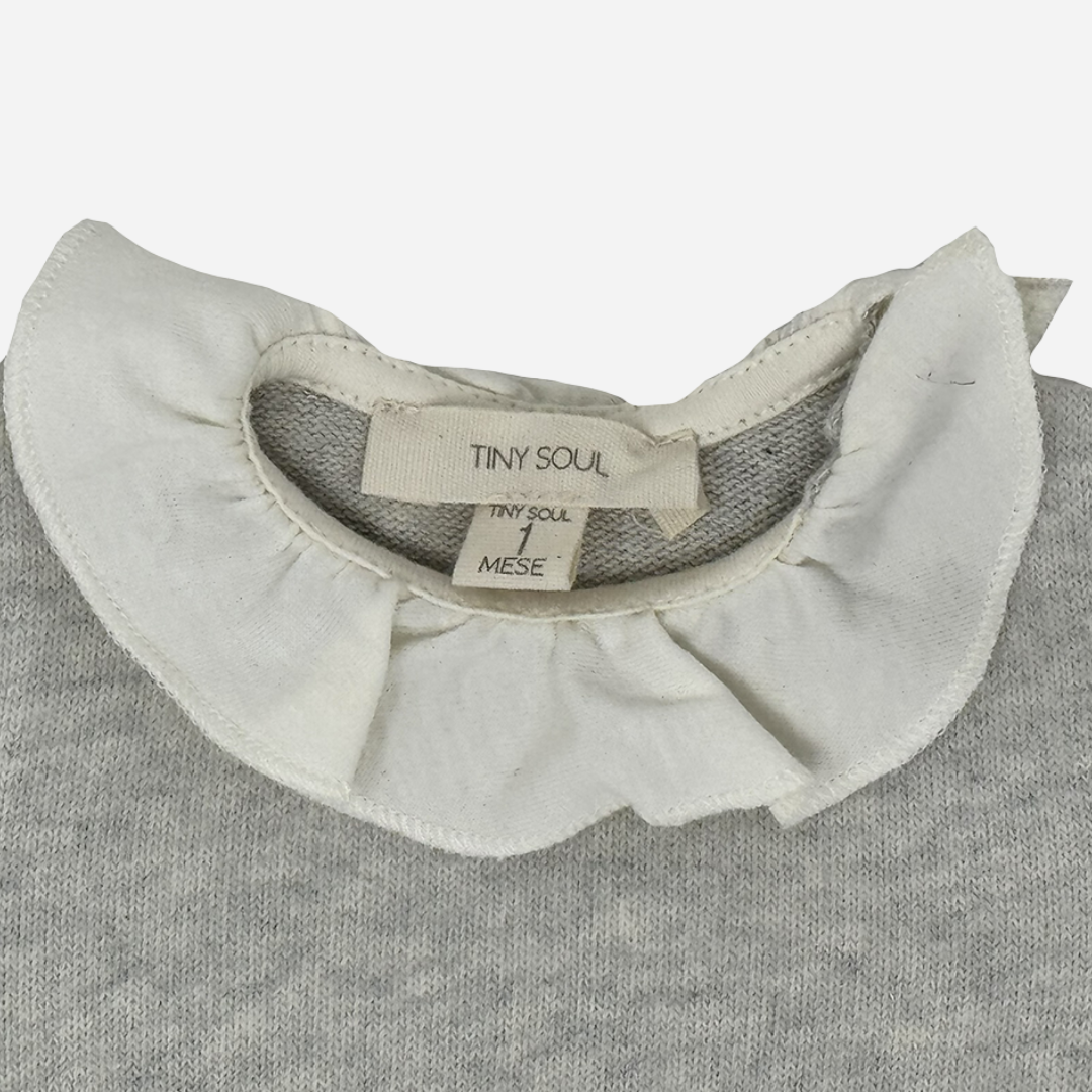 Sold at Bombon shop, designed by Tiny Soul — soft grey knit baby bodysuit with long sleeves and an ivory ruffled collar. zoom