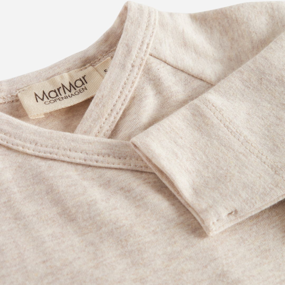 Sold at Bombon shop, designed by MarMar Copenhagen — beige organic cotton footed baby onesie with side tie closure.