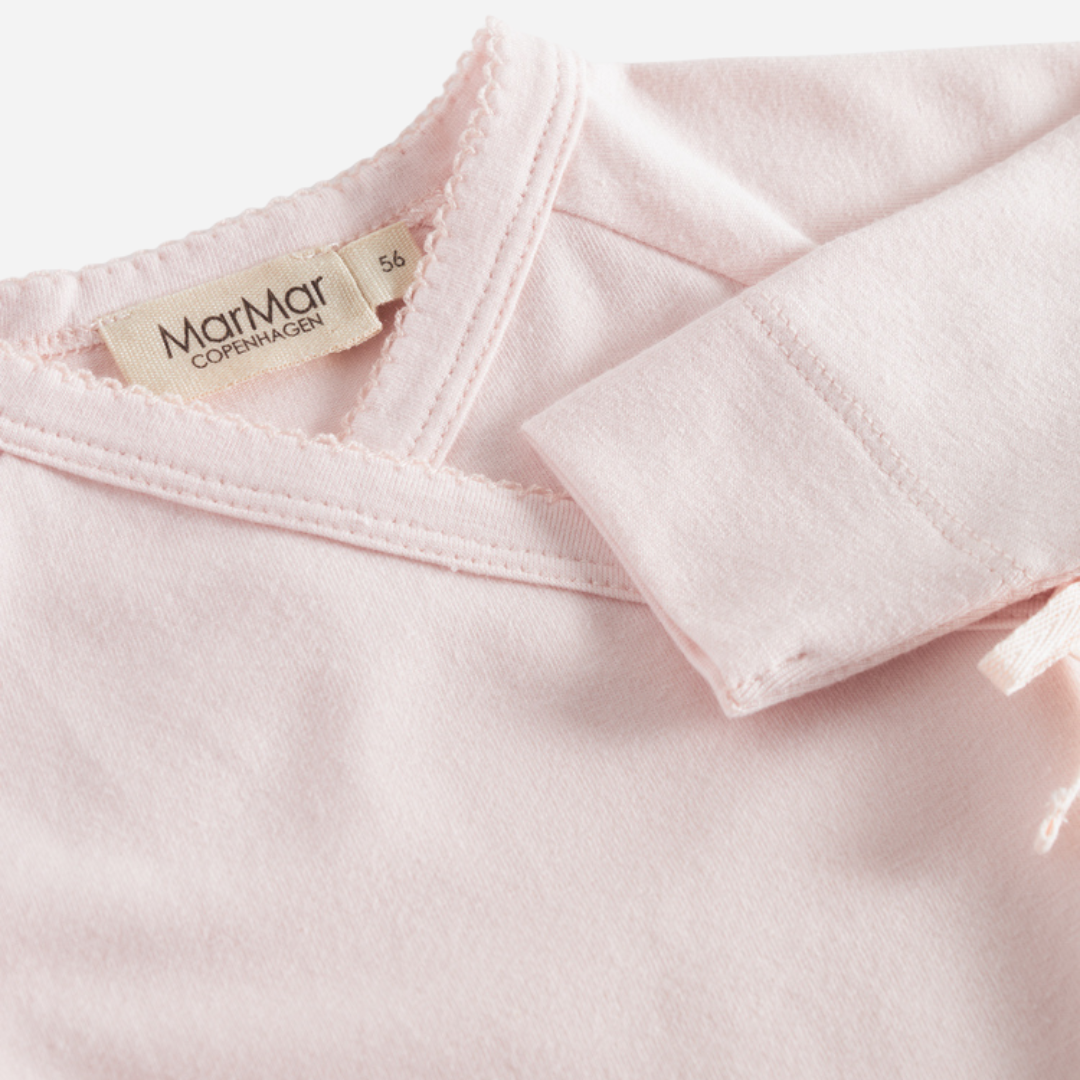 Sold at Bombon shop, designed by MarMar Copenhagen — blush pink organic cotton footed baby onesie with side tie closure.