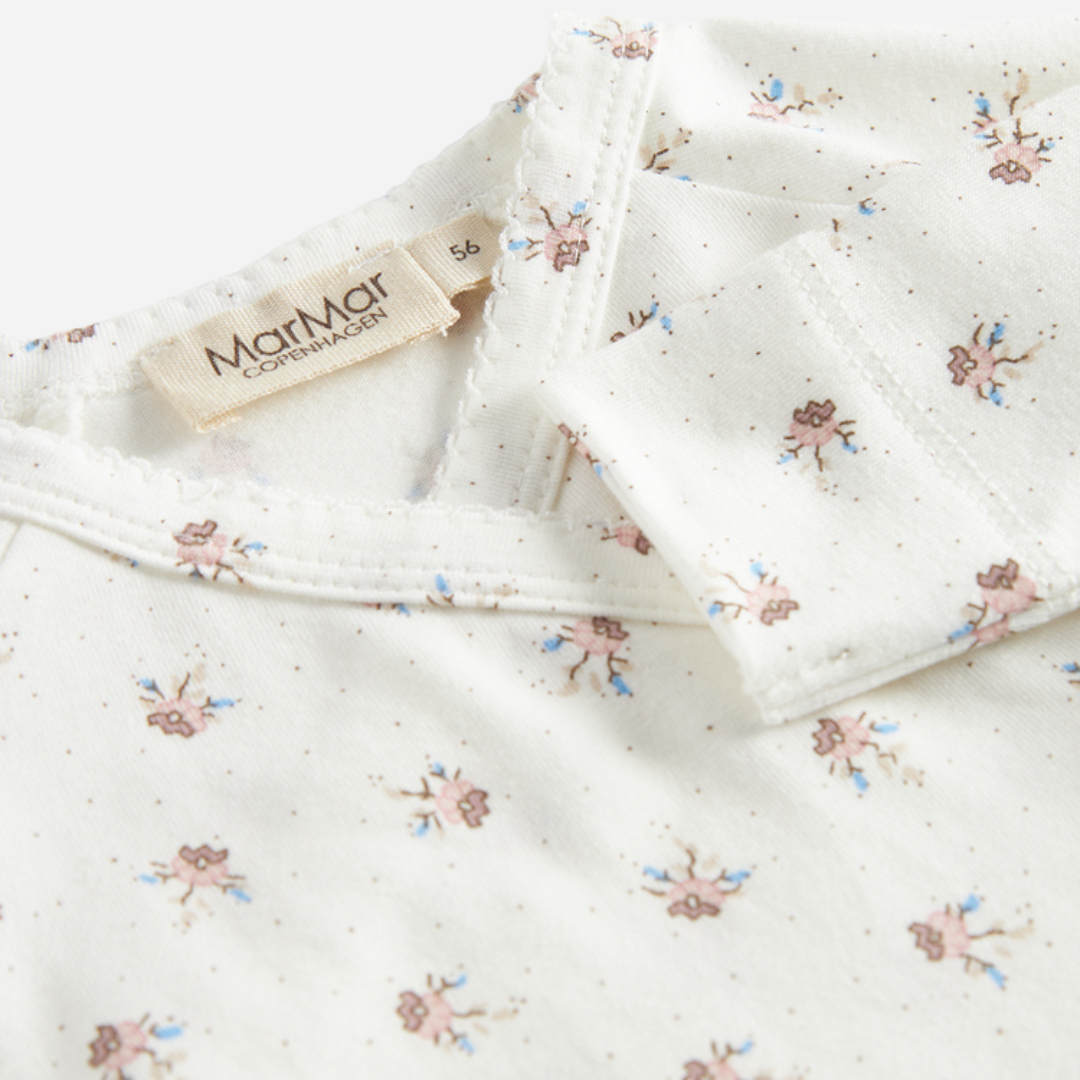 Sold at Bombon shop, designed by MarMar Copenhagen — white organic cotton baby onesie with floral print and side-tie closure, part of a matching set.