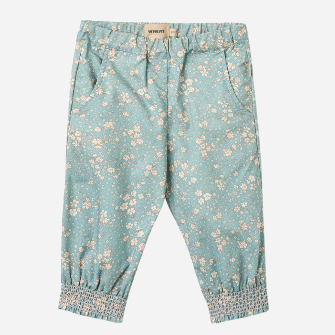 Sold at Bombon Shop, designed by Wheat, spring lake flowers organic cotton baby trousers in soft blue floral print with elastic waist and relaxed fit.